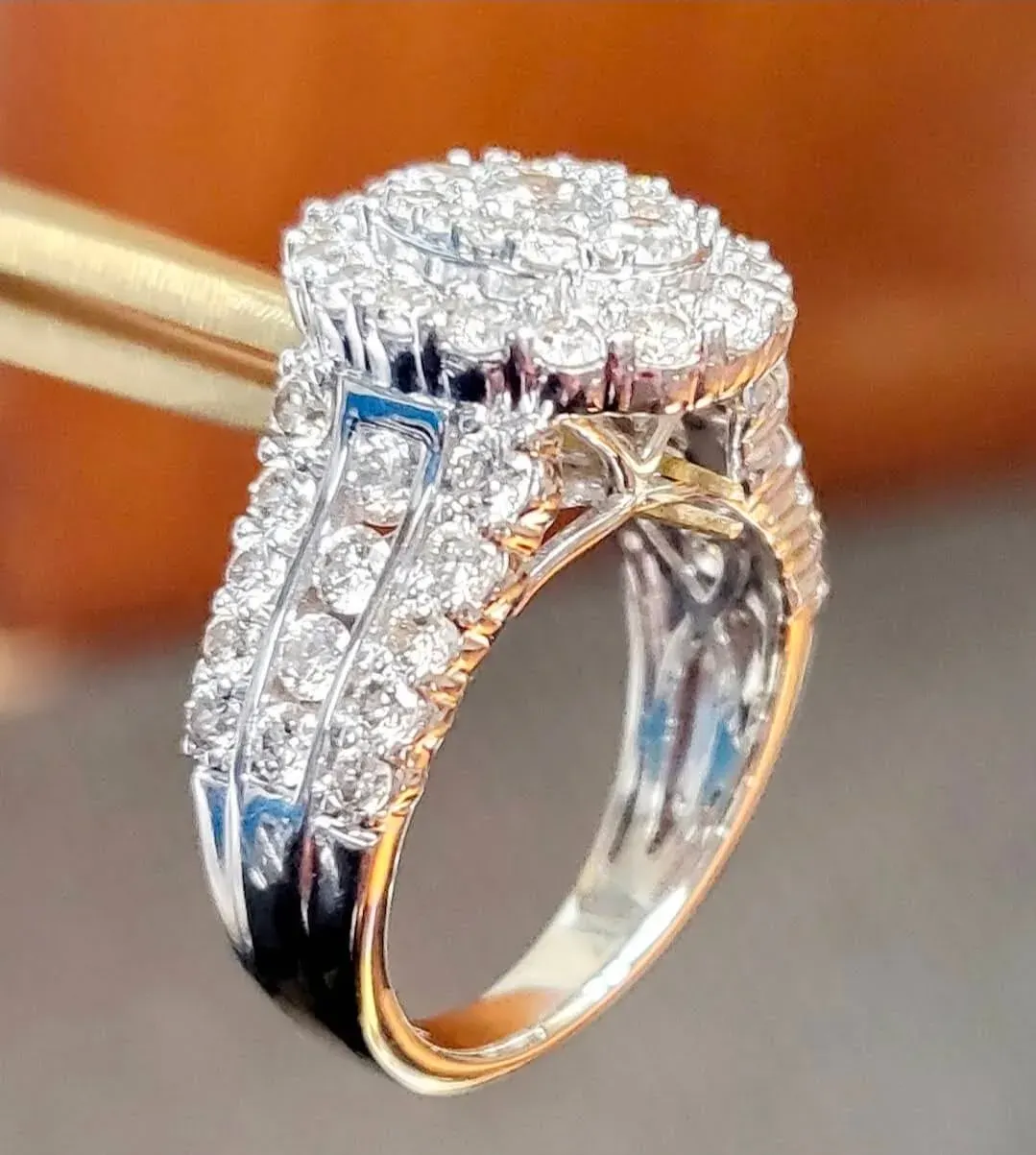 A white-gold diamond cluster ring with channel-set diamond shoulders.