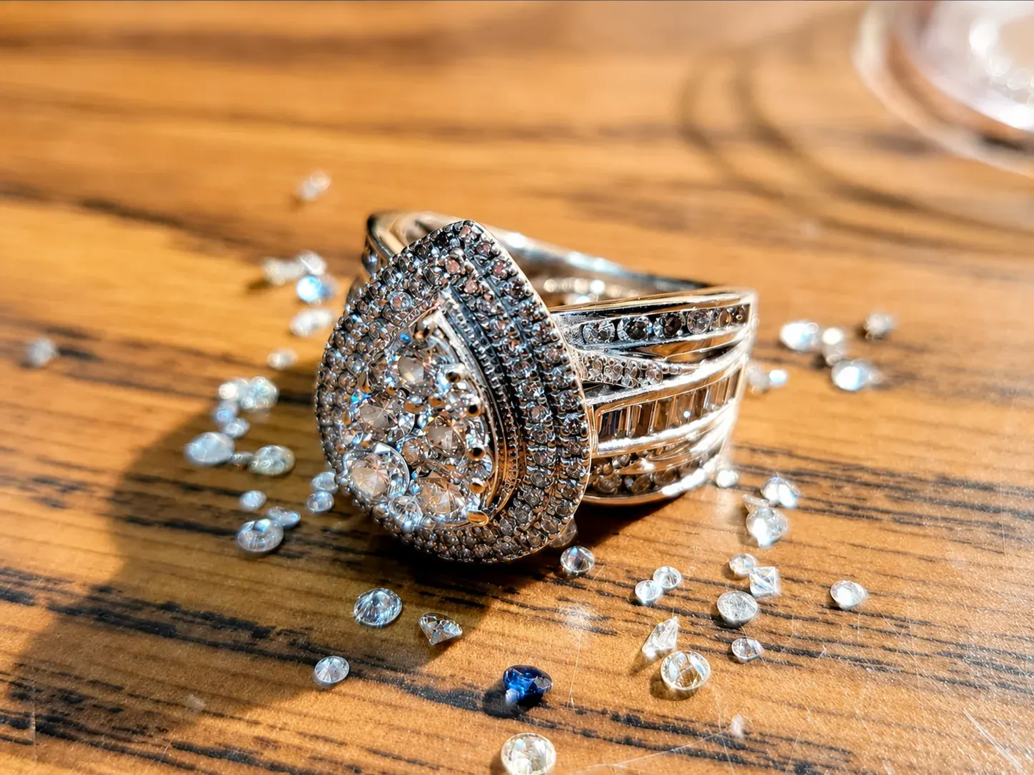 Diamond halo ring on a wood surface with loose stones.