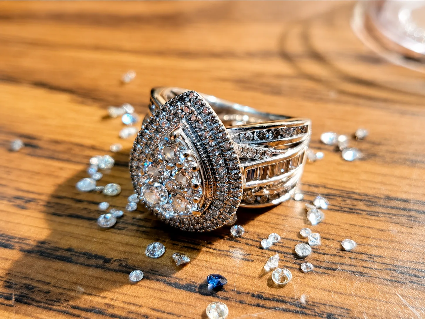 Diamond halo ring on a wood surface with loose stones.