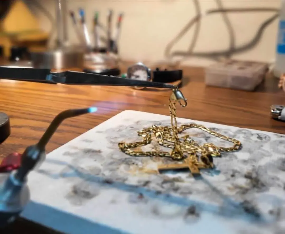 A gold Figaro chain being soldered at the jeweler’s bench.