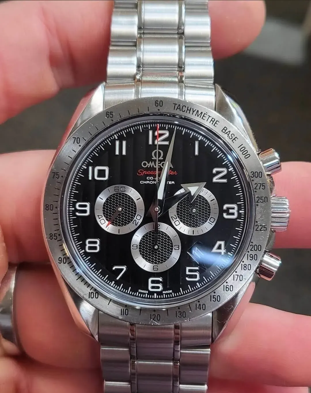 An Omega Speedmaster chronometer held in hand after service.