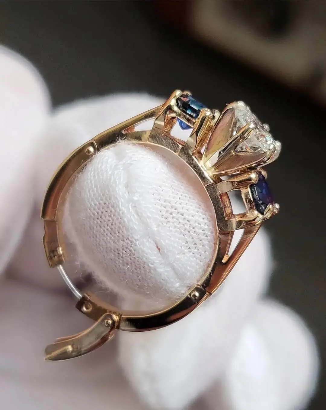 A gold ring set with a marquise diamond flanked by blue sapphires.