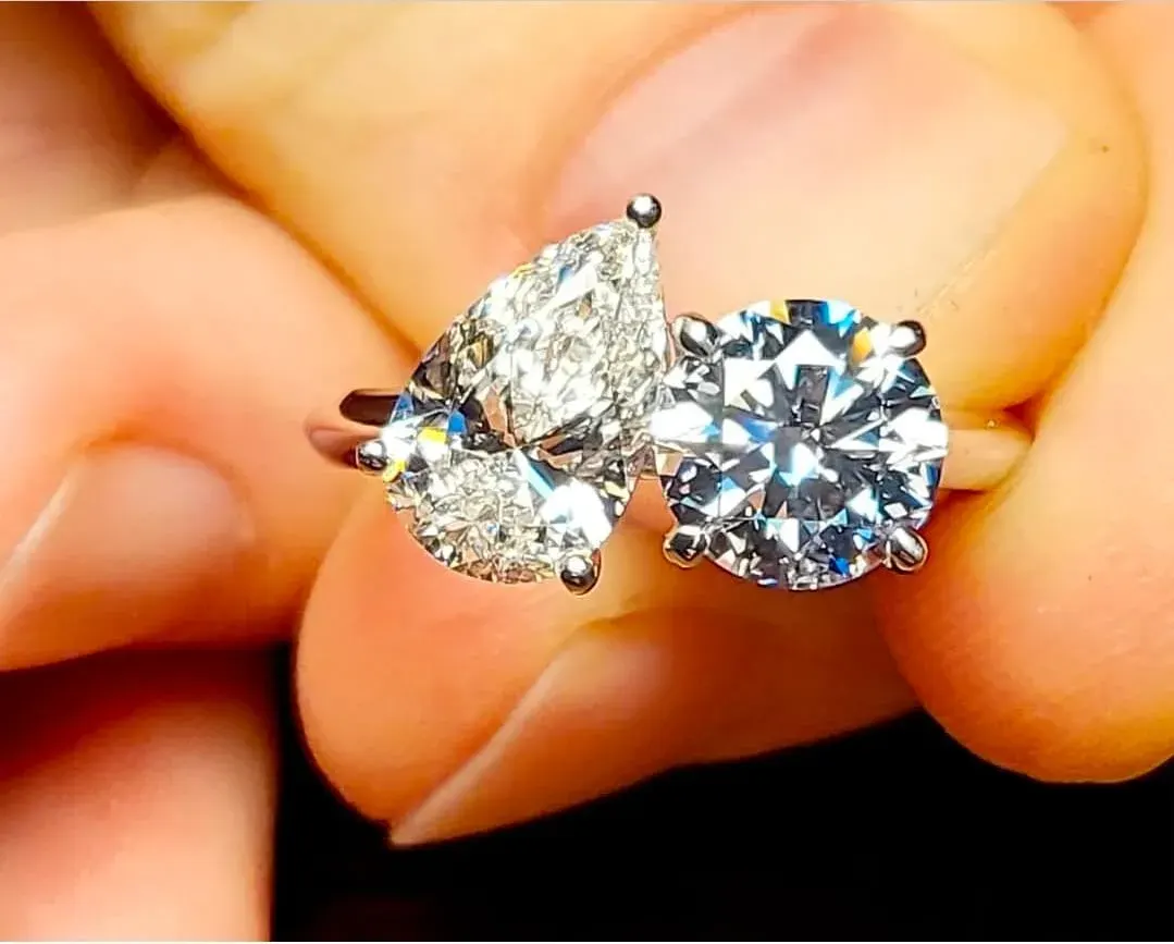 A toi et moi ring set with a pear diamond and a round diamond in white gold.